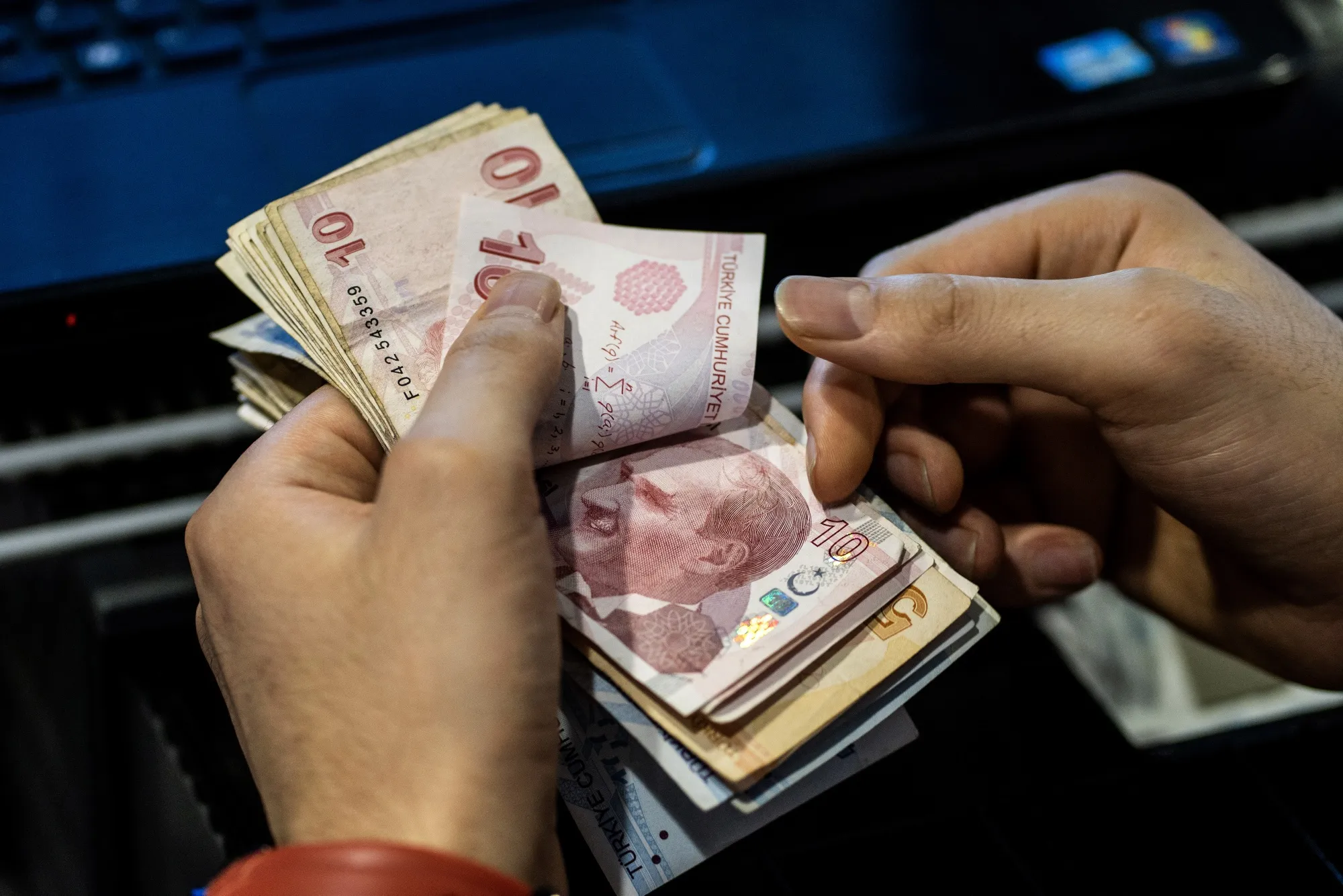 A cashier counts Turkish lira banknotes.