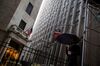 A pedestrian carries an umbrella while walking past the New York Stock Exchange (NYSE) in New York, U.S., on Wednesday, Feb. 24, 2016. U.S. stocks rose, benchmark indexes climbing back from declines of more than 1 percent as crude stabilized near $32 a barrel in New York.