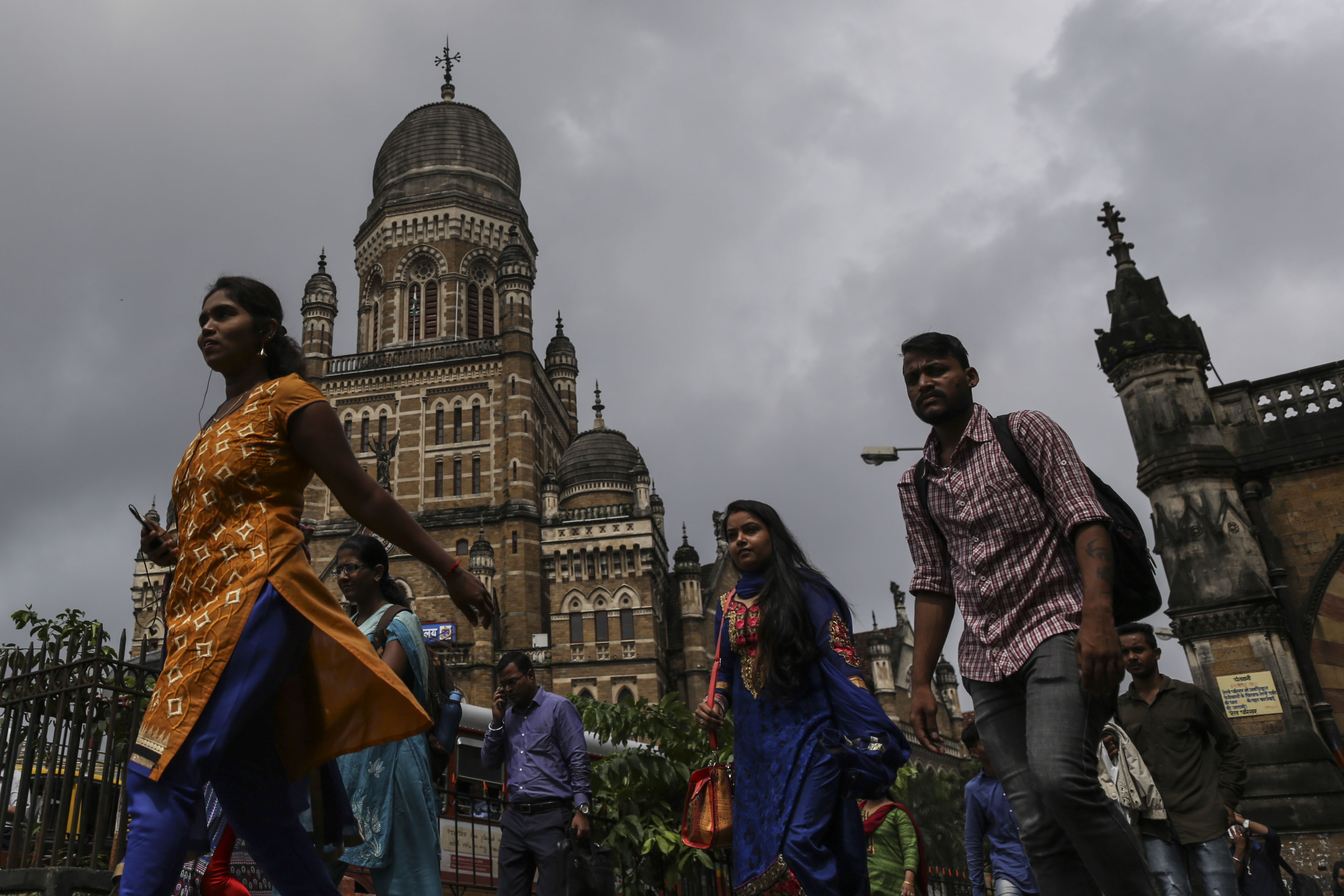 Commuters and pedestrians walk past the Chhatrapati Shivaji Terminus railway station in Mumbai, India.