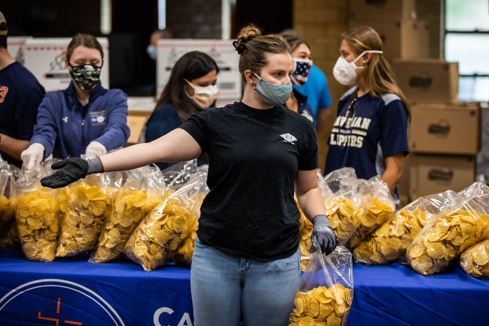A volunteer wearing a protective mask directs people at a Catholic Charities Brooklyn and Queens pop-up food pantry in the Brooklyn borough of New York, U.S., on Friday, May 29, 2020. 