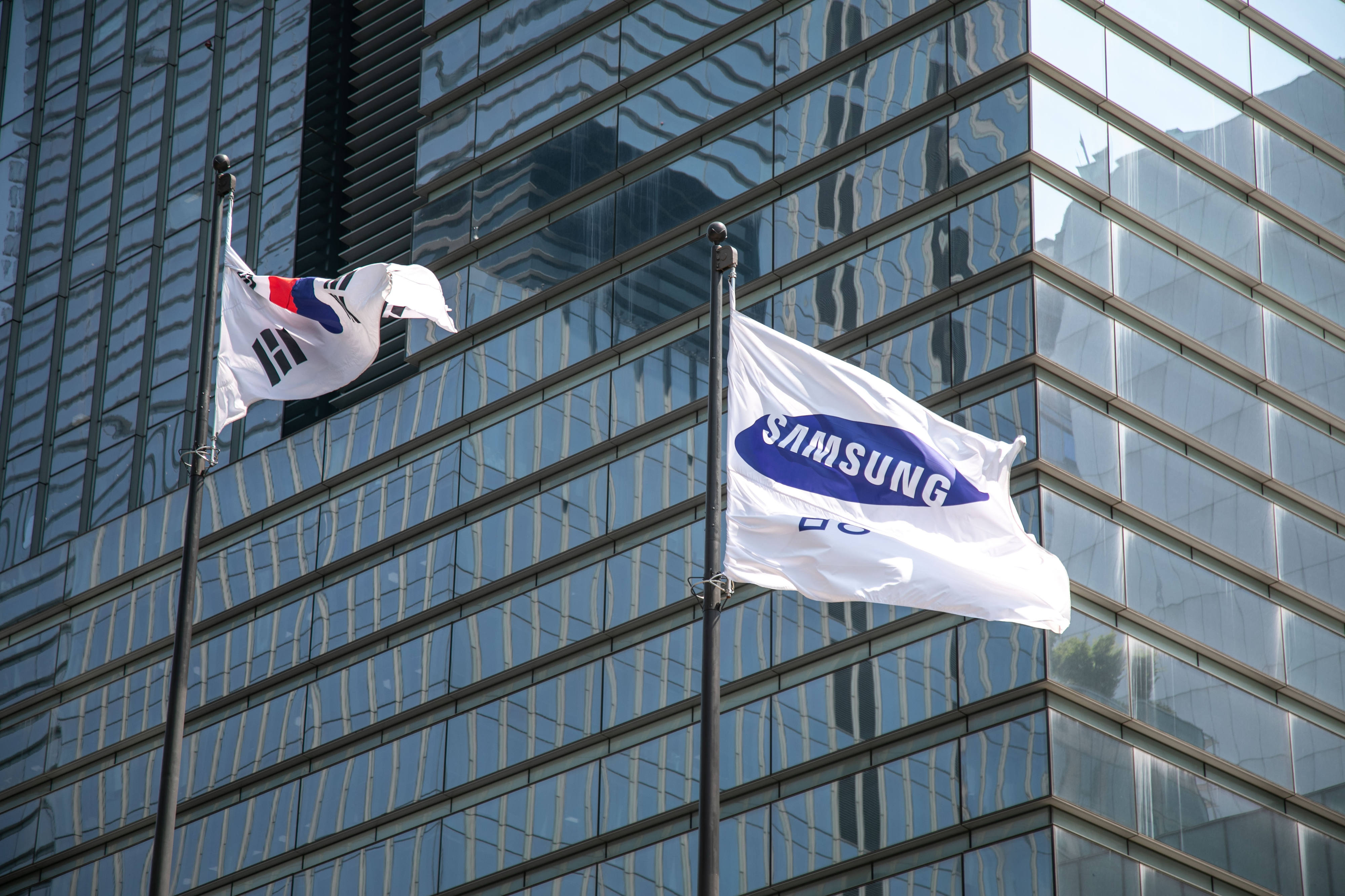 A South Korean flag, left, and a Samsung Electronics Co. flag flies outside the company's headquarters in Seoul, South Korea, on Friday, June 28, 2024. South Korea will begin awarding aid to chipmakers from July, kicking off a 26 trillion won ($19 billion) package of financial support pledged toward boosting a critical industry.
