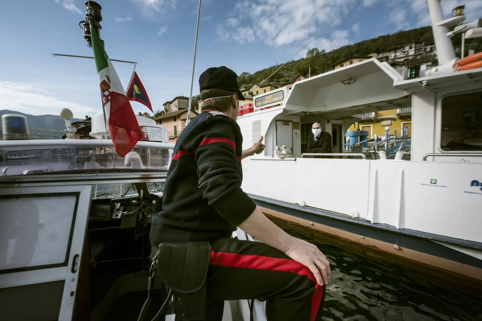 An officer from the Carabinieri's coastal boat patrol gestures to a passenger on a commuter boat on Lake Iseo in Brescia, Italy, on April, 13.