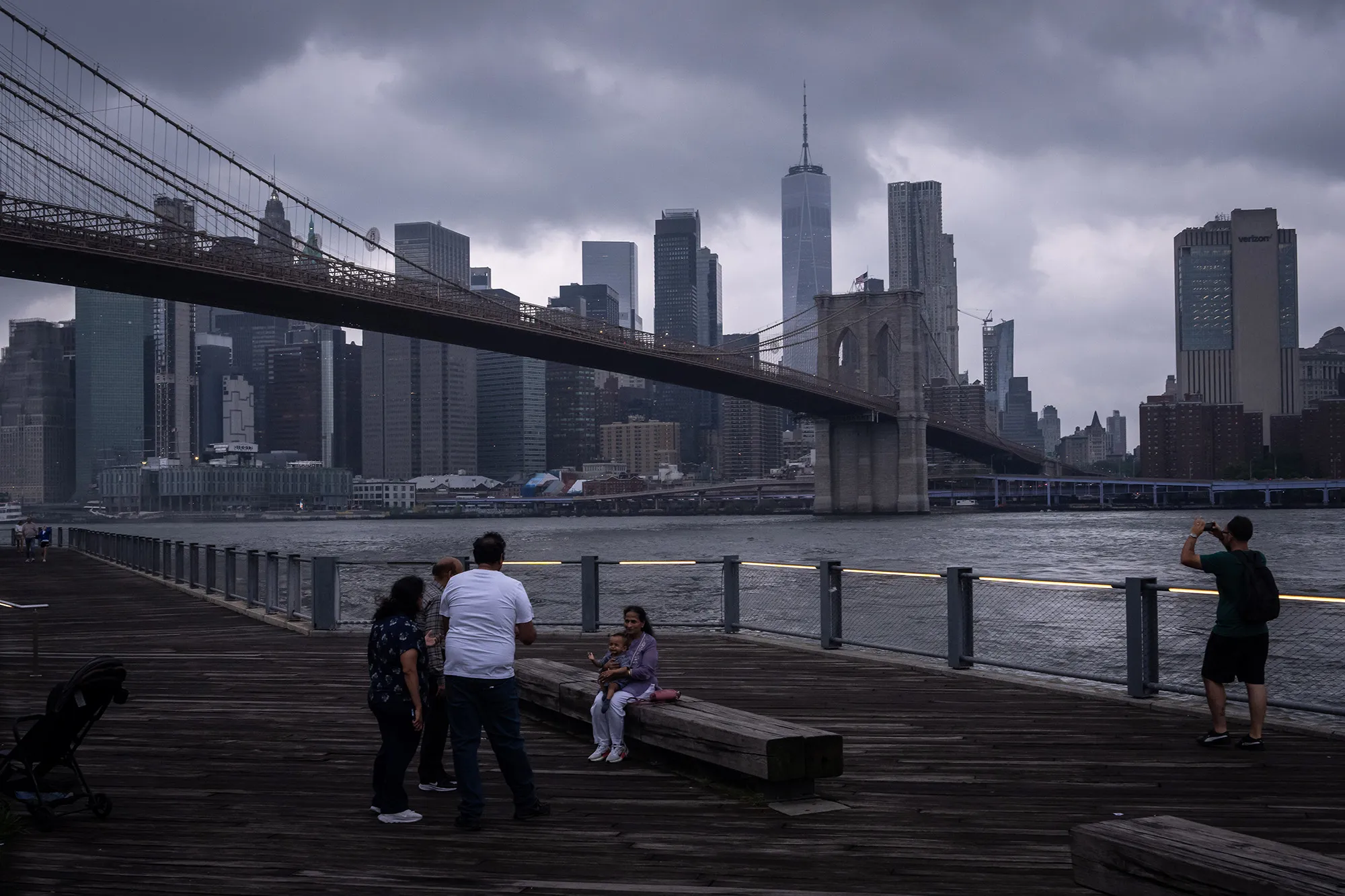 People gather near the East River in front of the Brooklyn Bridge during a break in the rain in the Brooklyn borough of New York City.&nbsp;