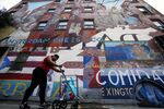 A woman pushes a car in front of &quot;The Spirit of East Harlem&quot; mural in New York City.