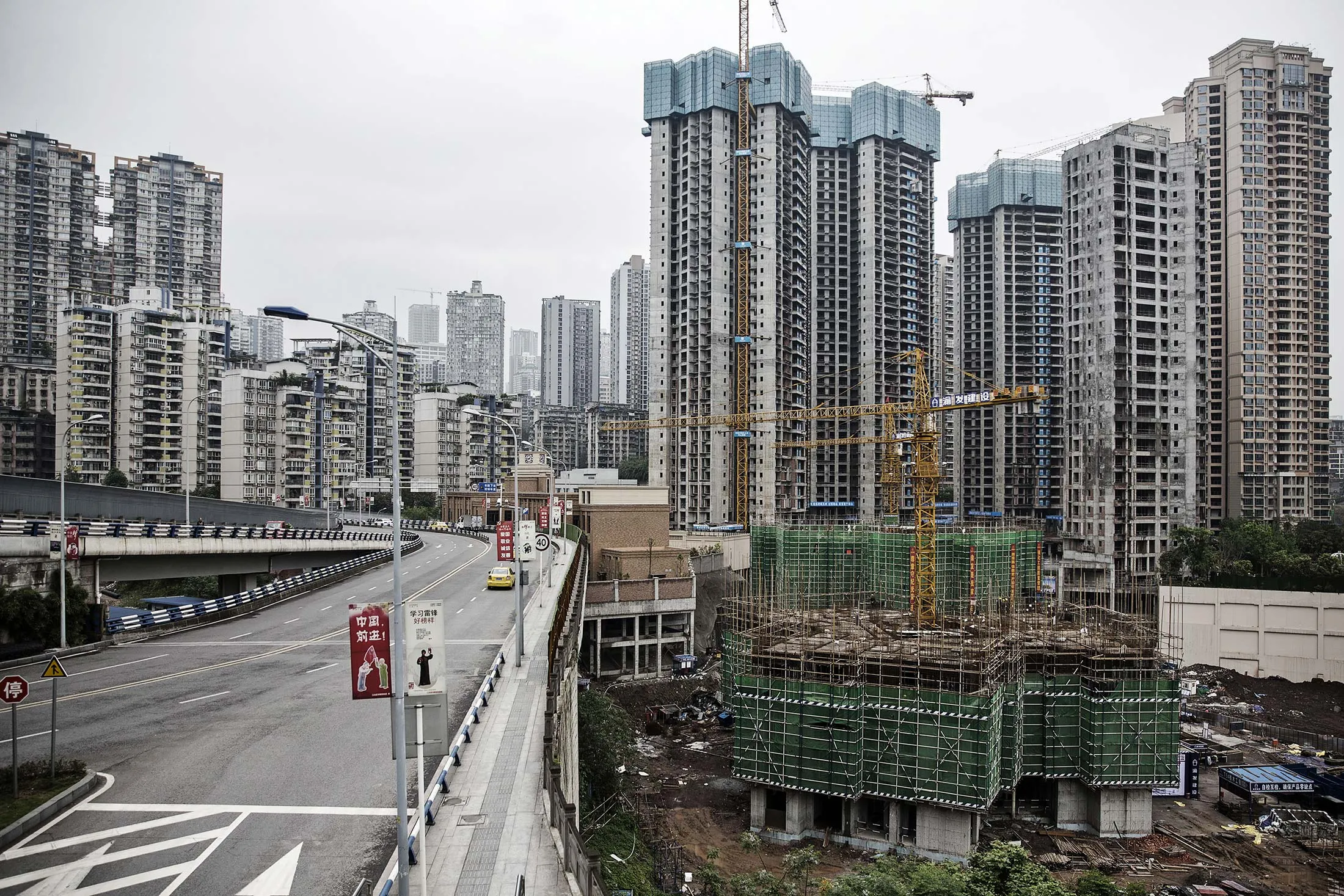 Cranes operate as residential buildings stand under construction in Chongqing, China, on Thursday, April 14, 2016.
