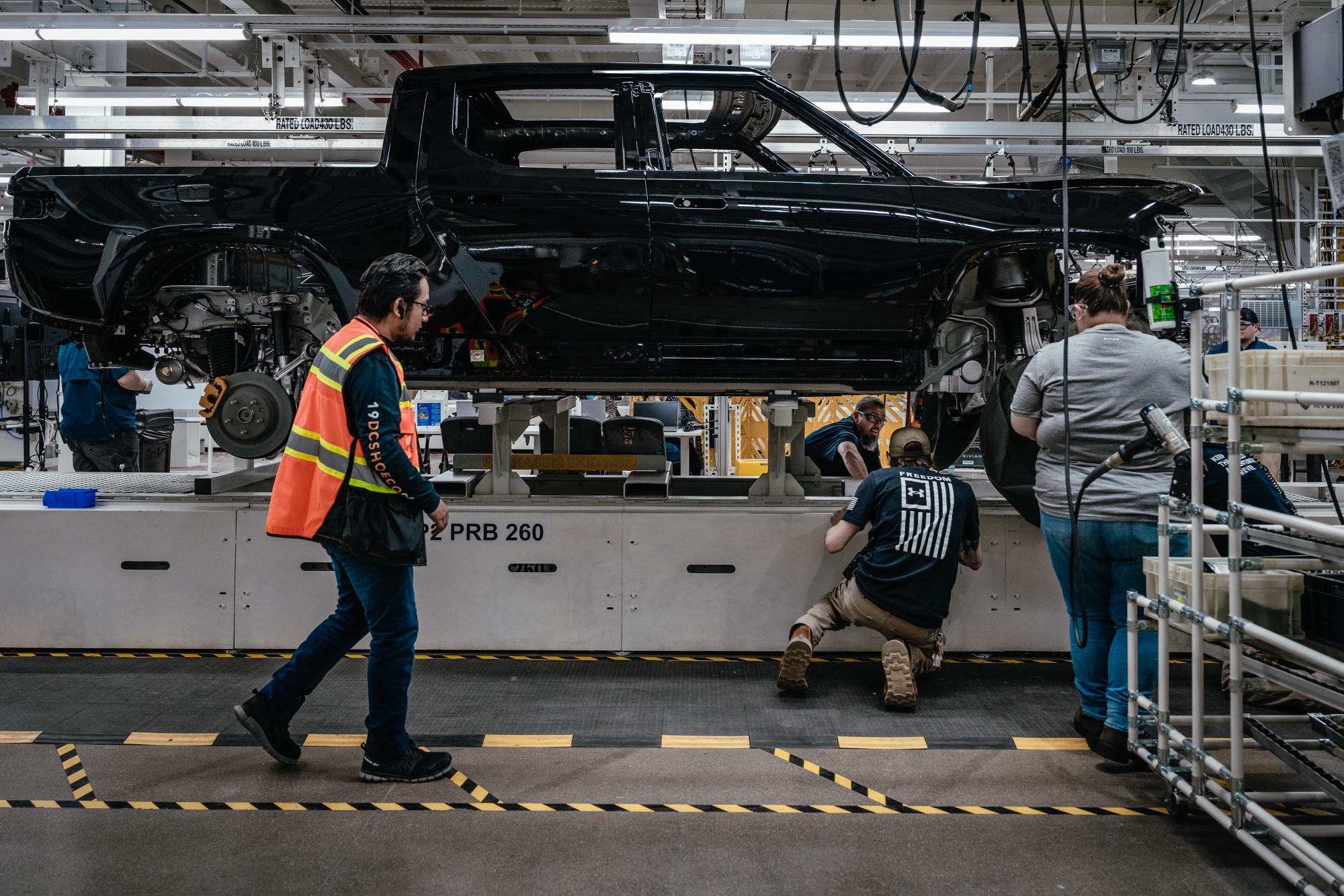 Workers assemble components of a Rivian electric vehicle pickup truck in Normal, Illinois.