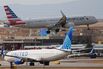 An American Airlines jet lands as a United Airlines plane waits for clearance to take off, at Denver International Airport in March.