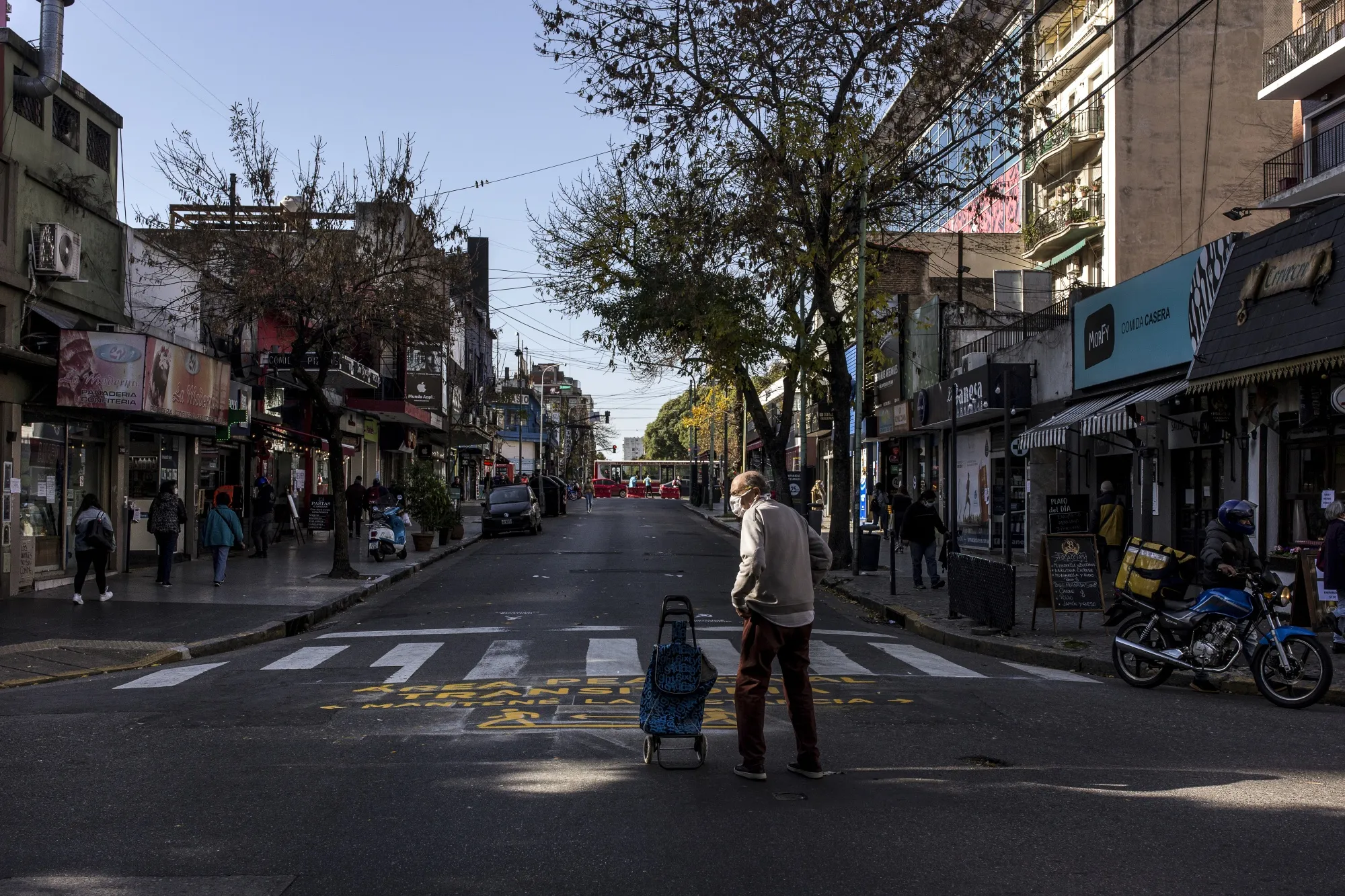 People wearing protective masks walk along a pedestrian-only street in&nbsp;Buenos Aires.