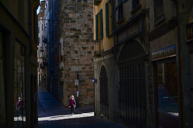 A woman wearing a protective mask walking along an empty street in Bergamo.