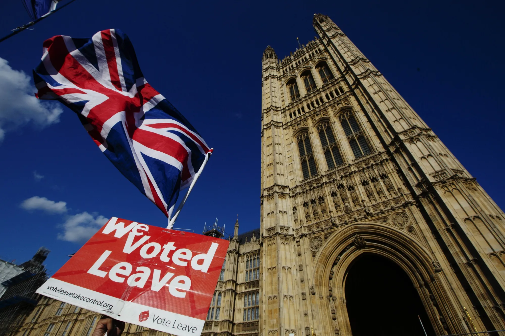 A Pro-Brexit demonstrator waves a flags while protesting outside the Houses of Parliament in London, U.K., Wednesday, Sept. 4, 2019.