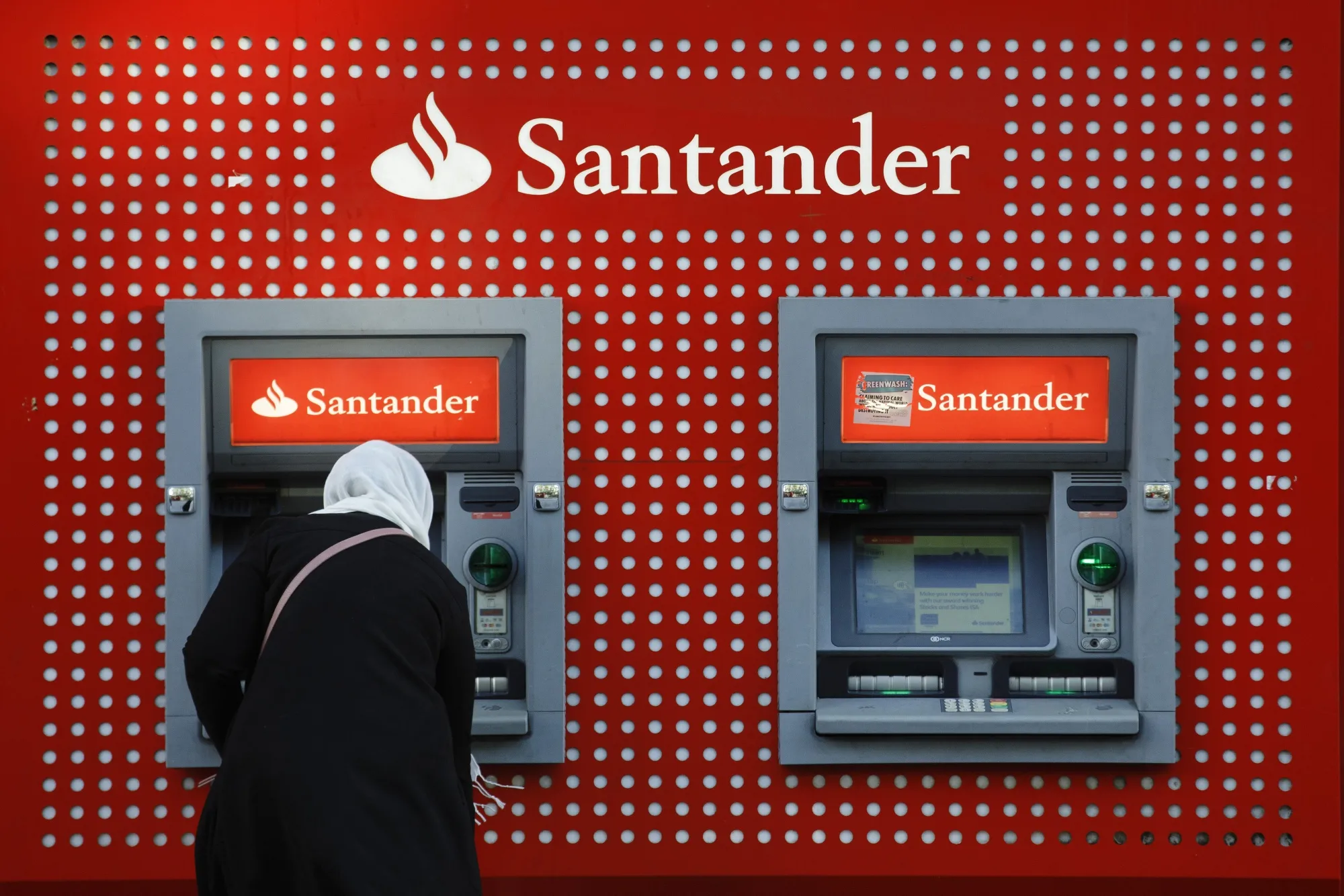 A customer uses an ATM&nbsp;at a Banco Santander&nbsp;branch in London.