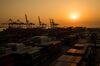Containers sit stacked beneath gantry cranes at the Sun Kwang Newport Container Terminal (SNCT) at sunset in Incheon New Port in Incheon, South Korea, on Friday, March 2, 2018.