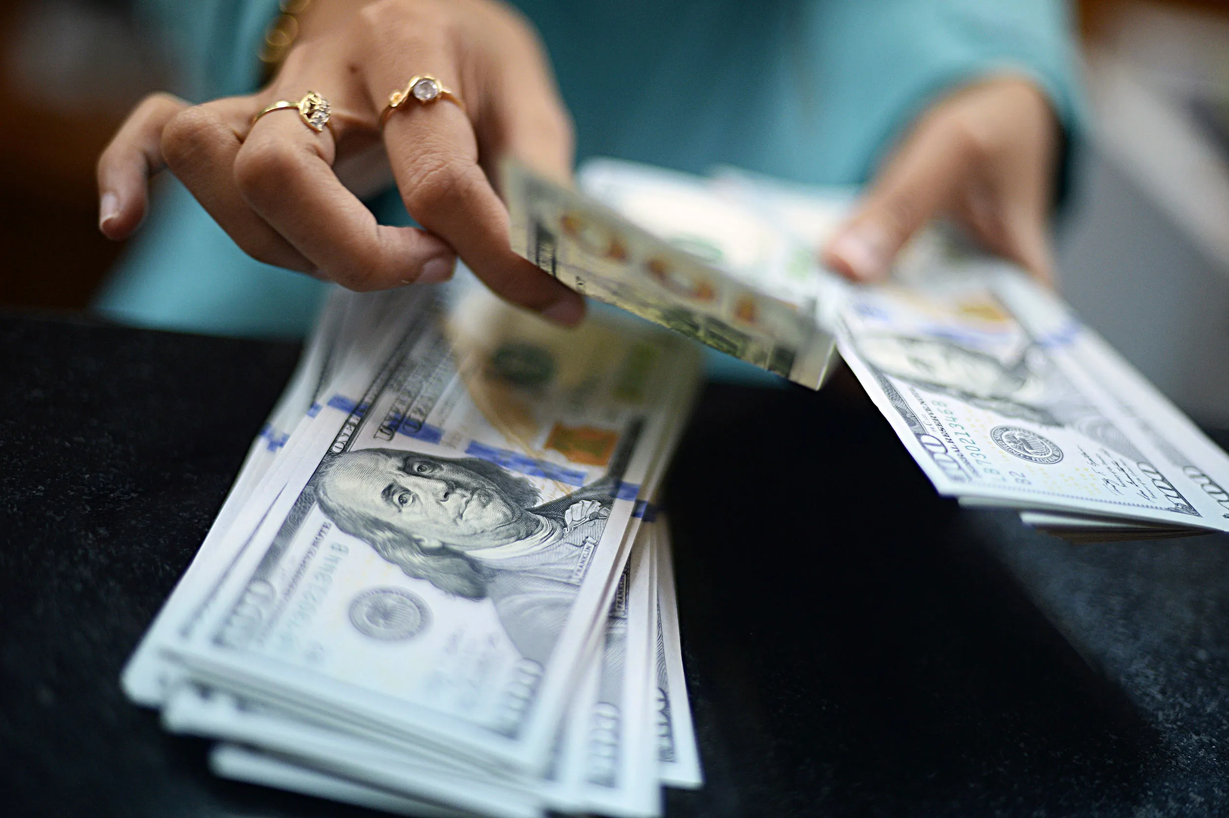 A clerk counts U.S. dollar banknotes at a currency exchange office in Jakarta.
