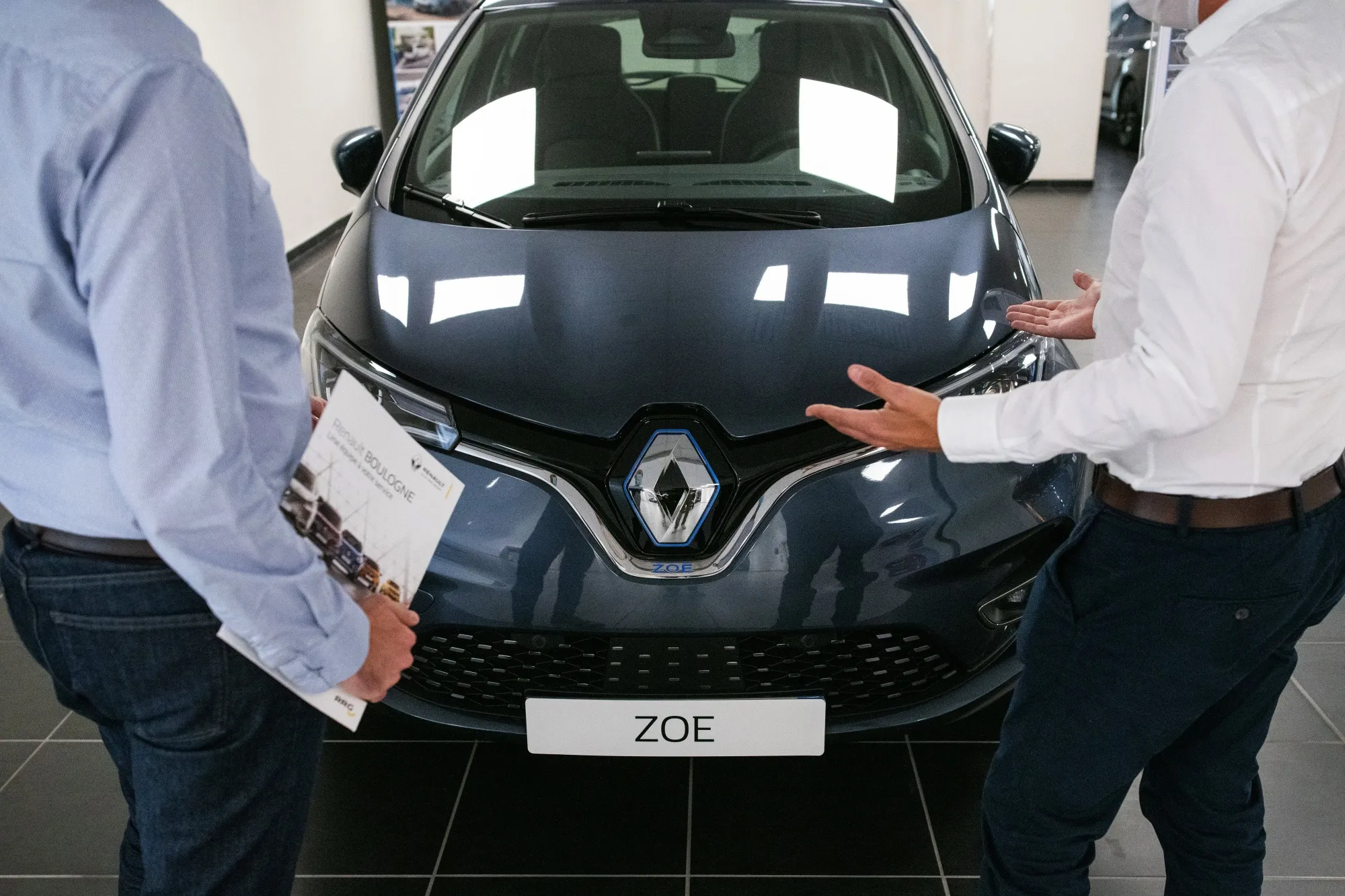 Employees beside a Renault Zoe R135 electric automobile inside a Renault SA showroom in Paris, France.