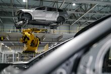 A large robotic arm carries an unfinished automobile to a second story conveyor belt at the Hyundai Metaplant