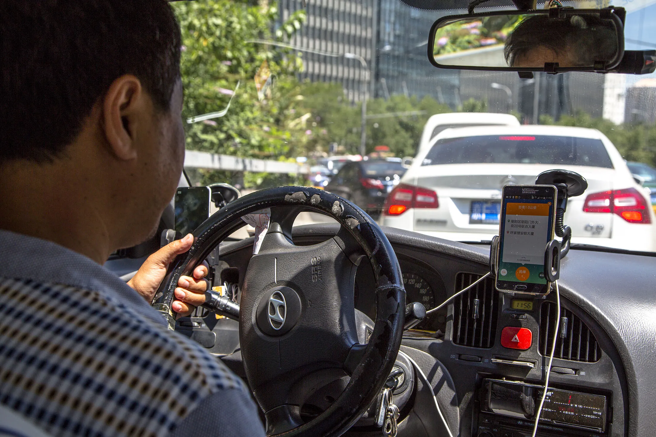 A taxi driver is using Didi Dacha App while driving in Beijing.
