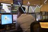 An employee monitors market data on computer screens as a stock ticker is reflected on a glass window inside the Indonesia Stock Exchange (IDX) in Jakarta, Indonesia.