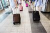 Travelers pull luggage while walking through LaGuardia Airport (LGA).