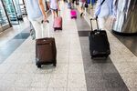 Travelers pull luggage while walking through LaGuardia Airport (LGA).