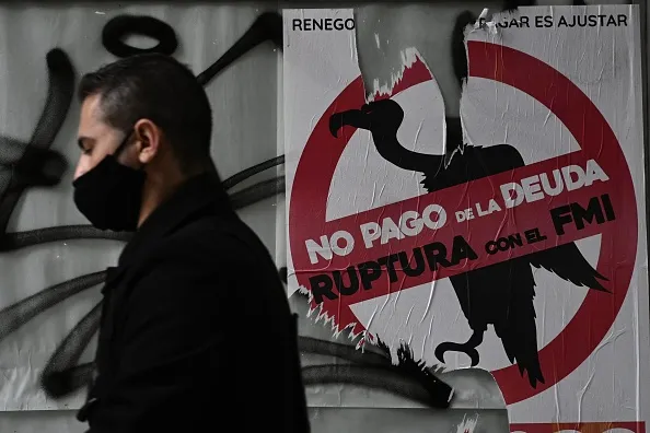 A man walks past a sign against paying the debt with the IMF in Buenos Aires