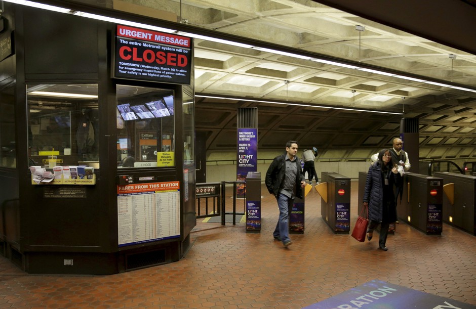 Commuters pass a sign announcing a 29-hour shutdown for an emergency safety investigation of power cabling of the entire Washington Metro system.