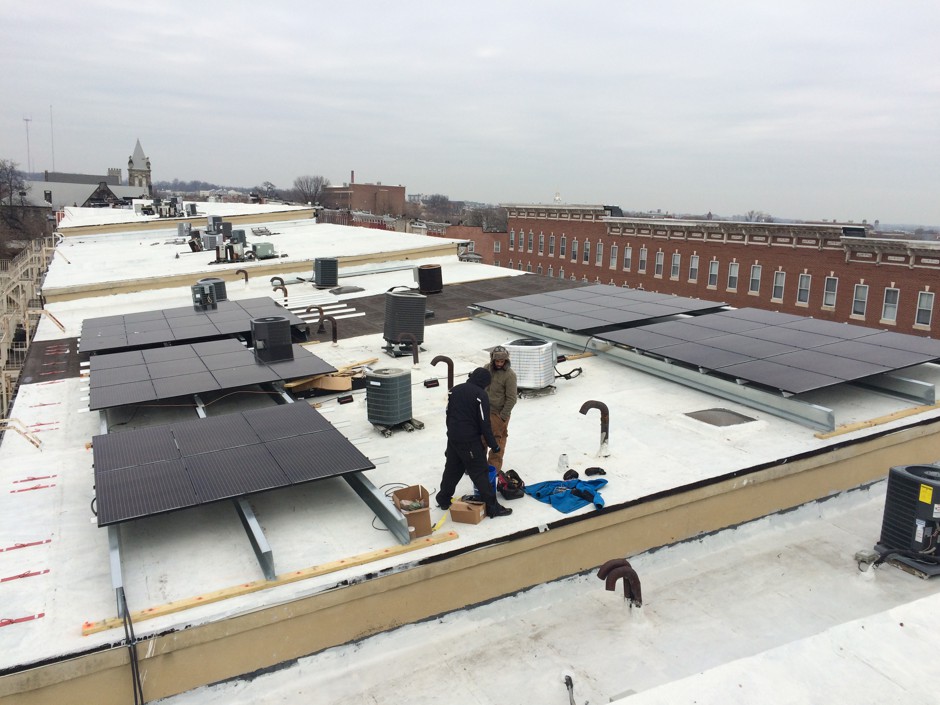 Solar panel installers work on the rooftops of some of Baltimore's poorest neighborhoods.