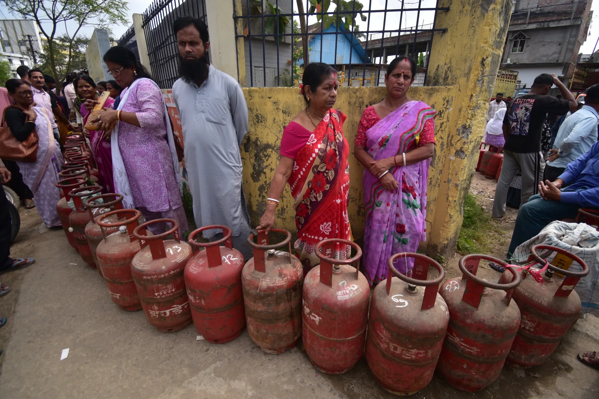 People wait in line with empty gas cylinders to collect LPG-filled gas cylinders in Assam, on March 19.