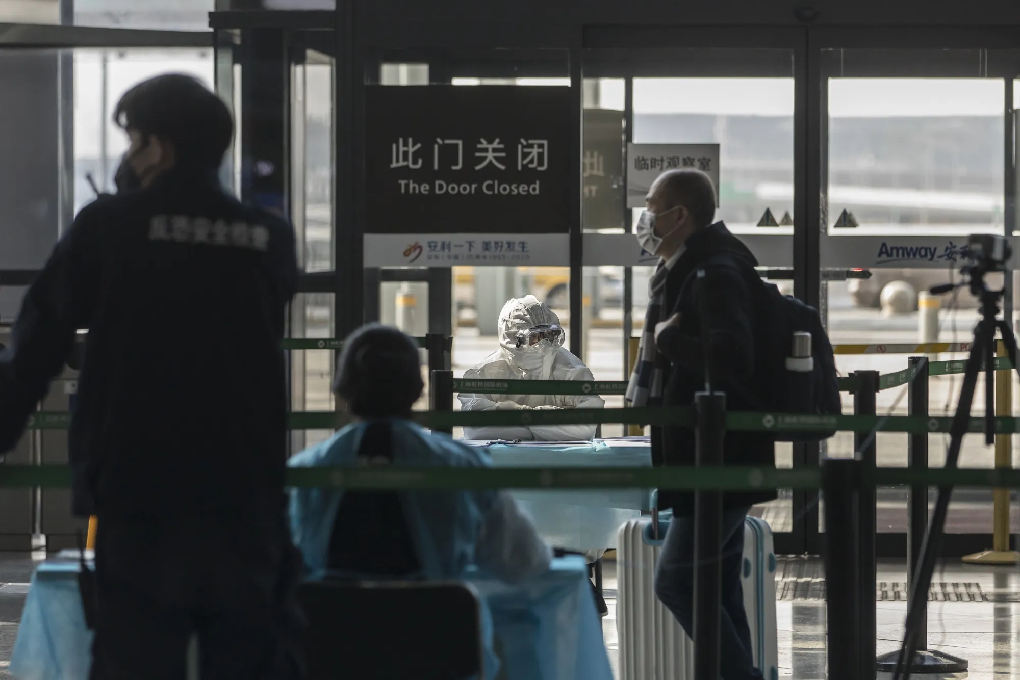Health workers in protective suits man a temperature check point for departing travelers at the Hongqiao International Airport in Shanghai.
