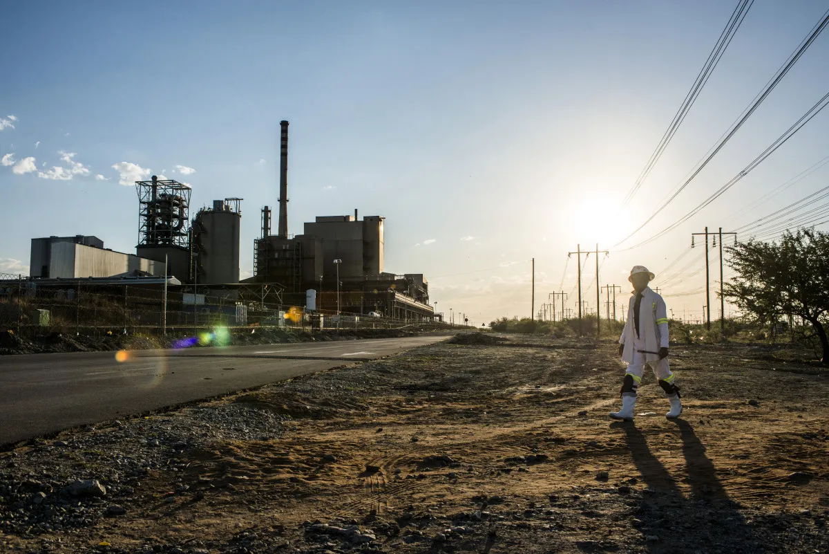 A worker walks past the Marikana platinum mine, operated by Lonmin Plc, in Marikana, South Africa.