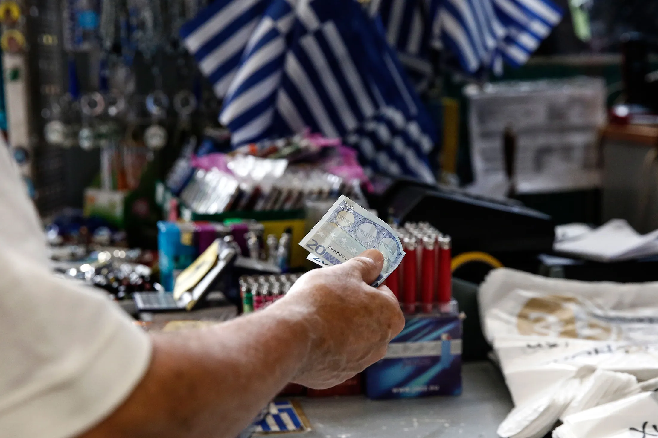 A customer offers a 20 euro note in payment for goods purchased inside a one euro store in Athens, on July 17.
