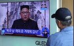 A man watches a television screen showing a broadcast featuring North Korean leader Kim Jong-un.