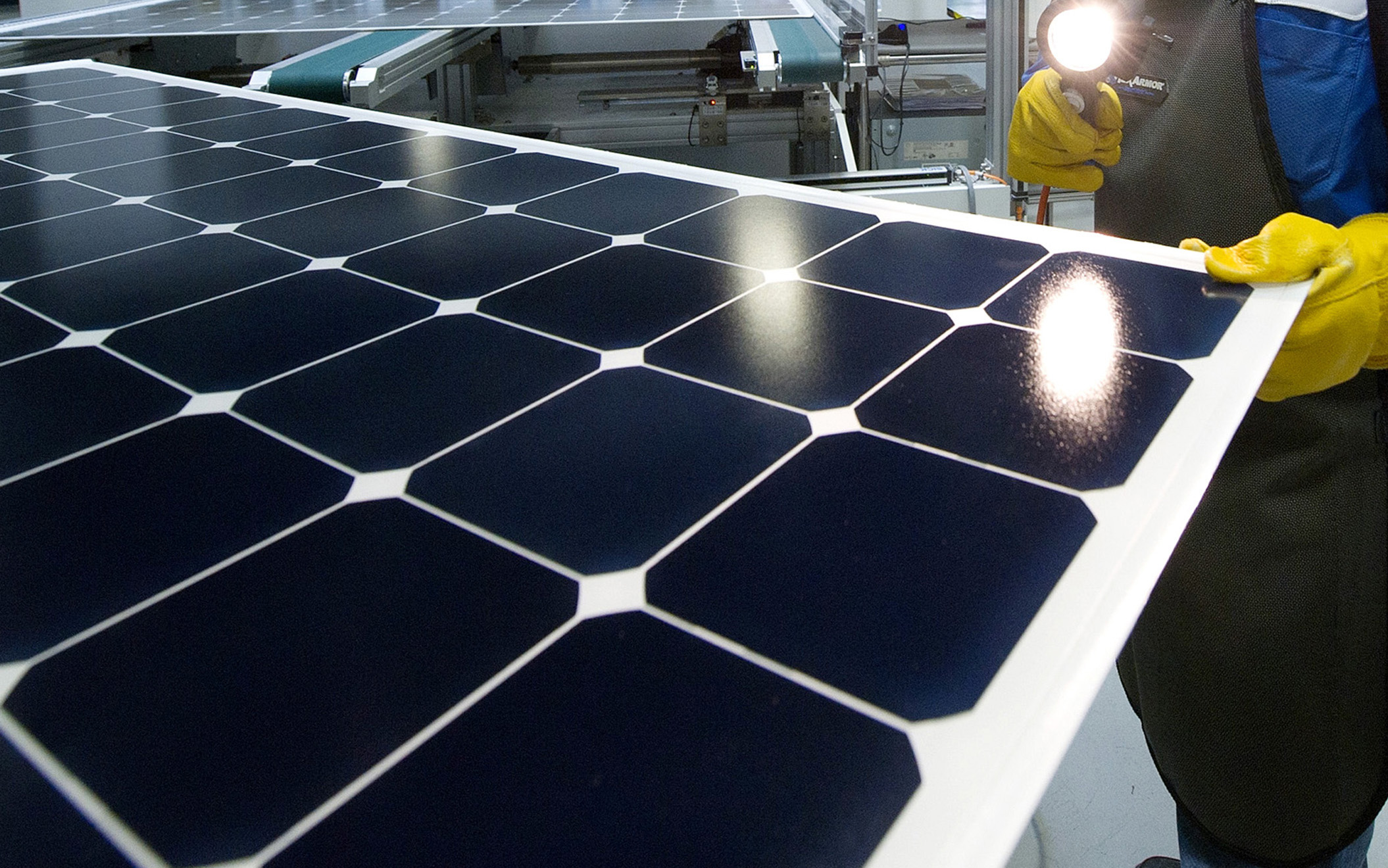 A solar panel is inspected at a module manufacturing plant.