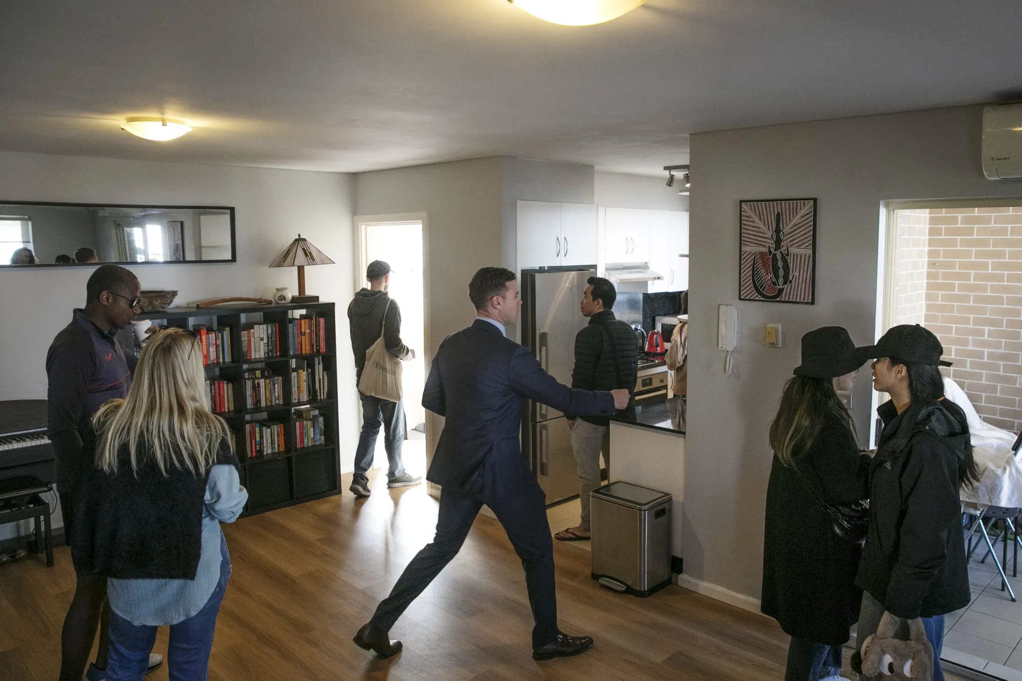 An agent attends to groups of potential tenants visiting an apartment unit for property inspection in Sydney.