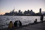 People sit on a dock along the skyline during sunset in Toronto, Ontario, Canada, on&nbsp;June 19.&nbsp;