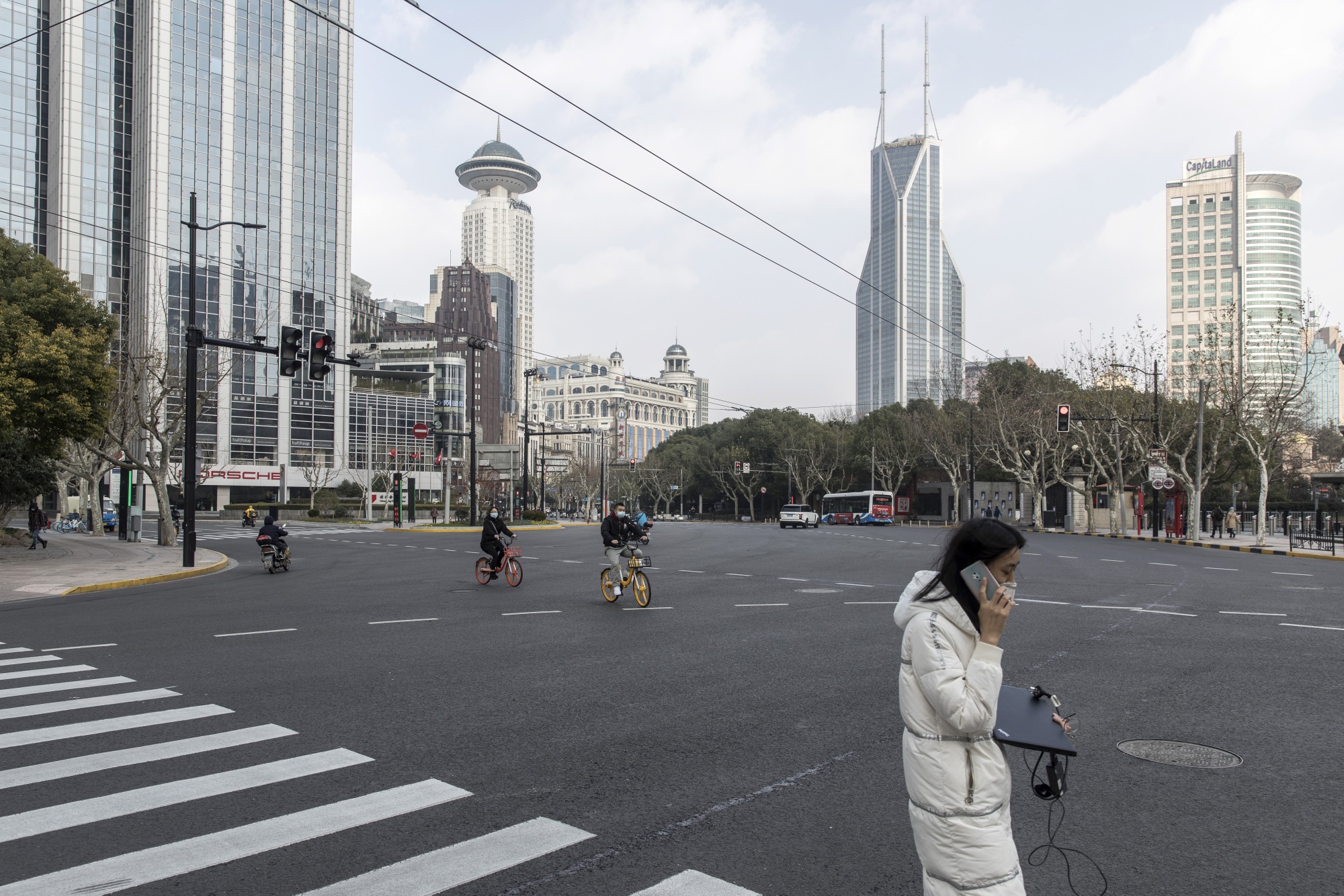 A woman carrying a laptop and smartphone crosses a near empty Nanjing Road, Jan. 29.