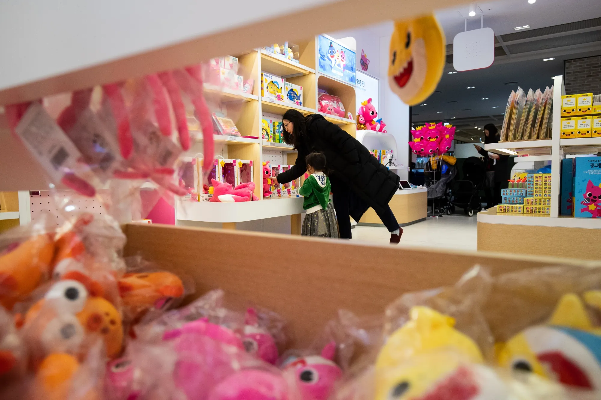 A woman and her child look at soft toys at a store in South Korea.