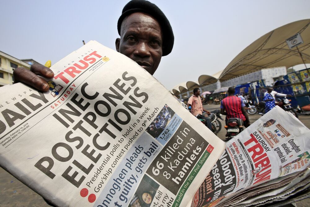 A man sells copies of a newspaper with a headline on the elections postponement in Lagos, Feb. 16.