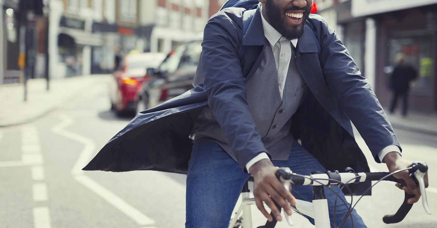 Smiling young businessman commuting, riding bicycle on sunny urban street