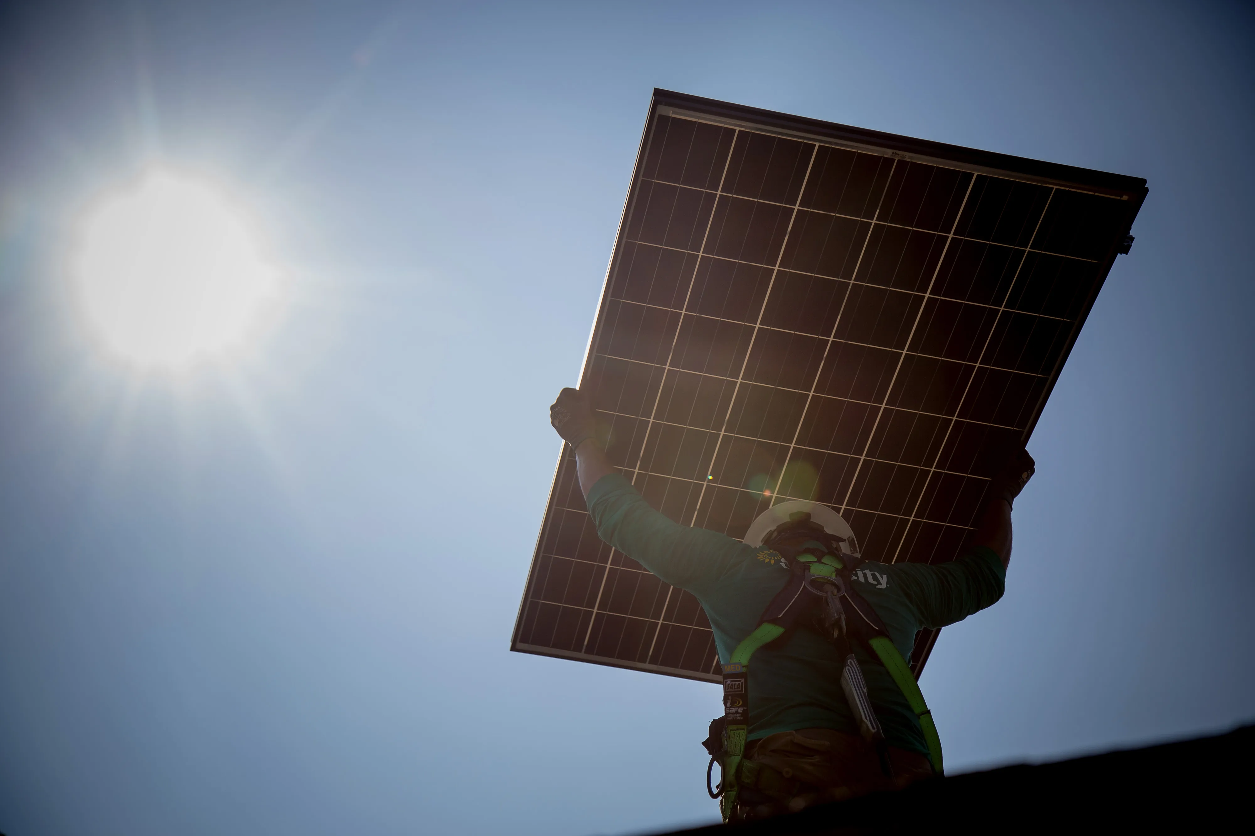 A worker&nbsp;carries a solar panel on the roof during installation at a home in New Jersey.