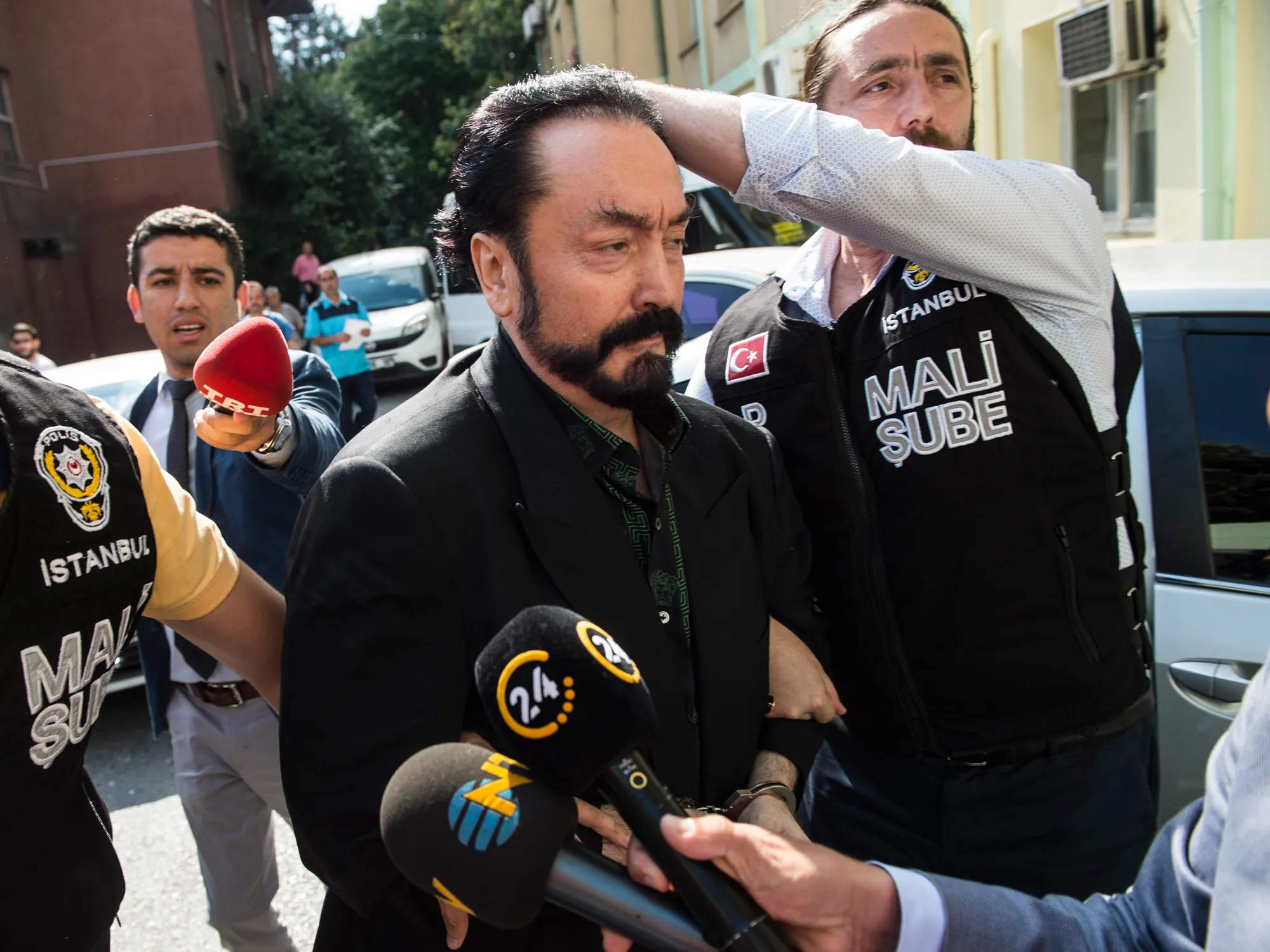 Police officers escort Adnan Oktar after his arrest, in Istanbul, in 2018.