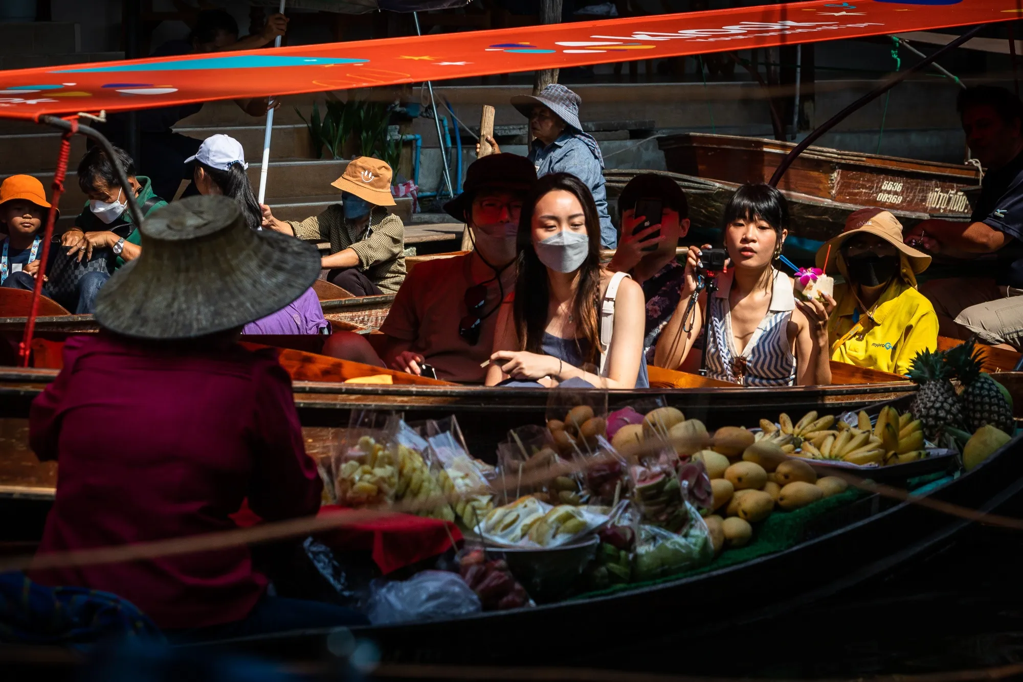 Tourists ride past a vendor at a floating market in Damnoen Saduak, Thailand.