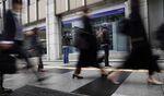 A pedestrian takes a photograph of an electronic stock board outside a securities firm in Tokyo, Japan.