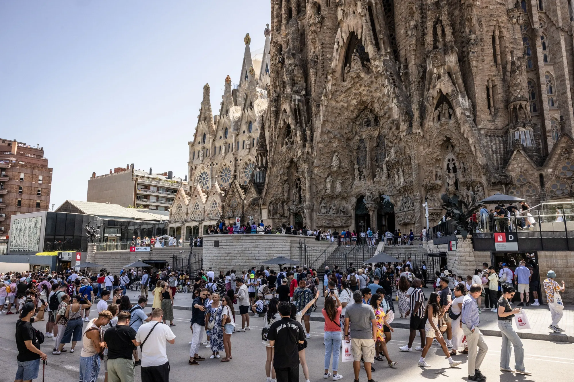 Tourists in the shade of the Sagrada Familia church in Barcelona.