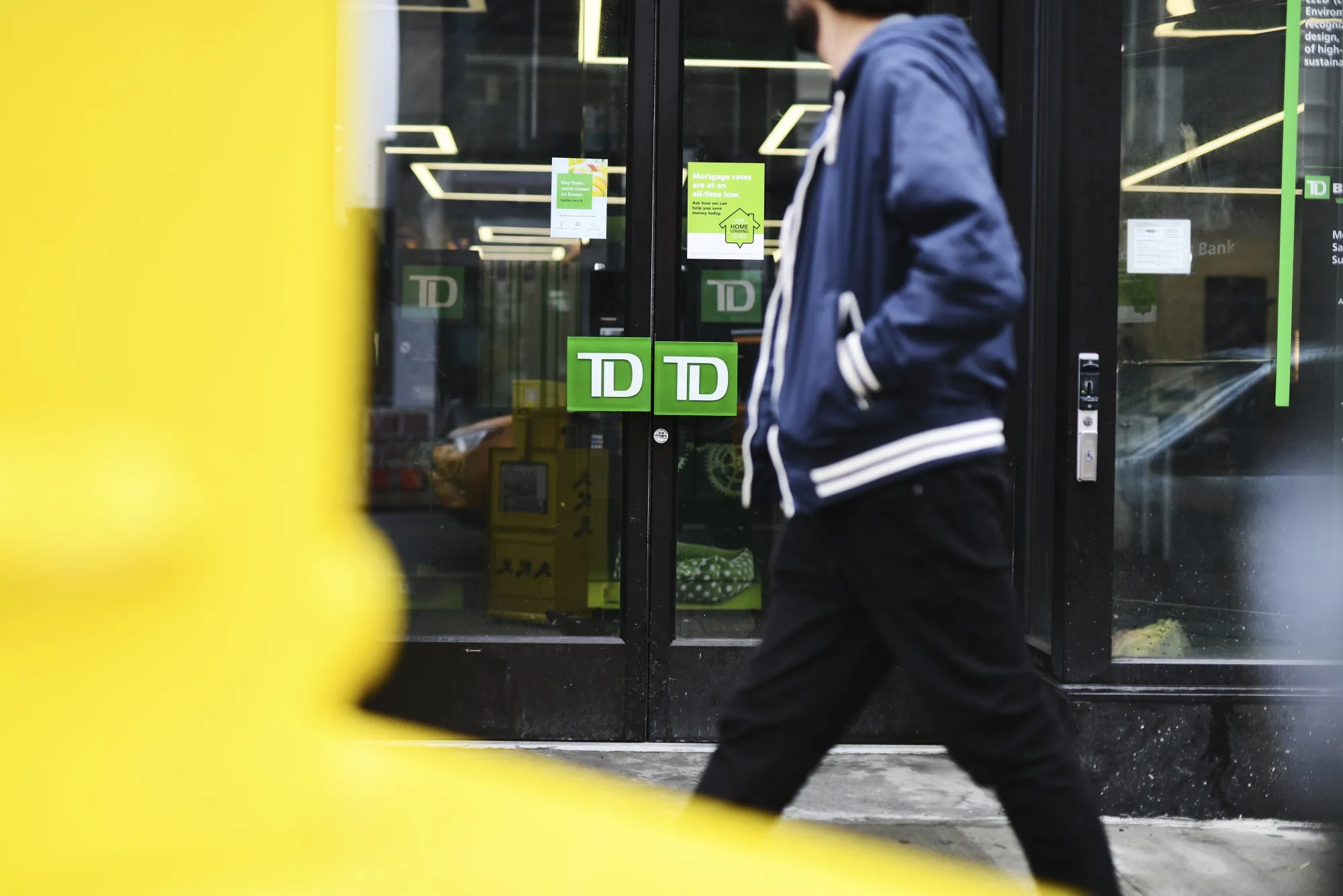 A pedestrian passes in front of a TD Ameritrade Holding Corp. bank branch in New York, New York.
