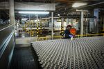 A worker&nbsp;lifts an aluminum can from the production line at a manufacturing plant in Springs, South Africa.