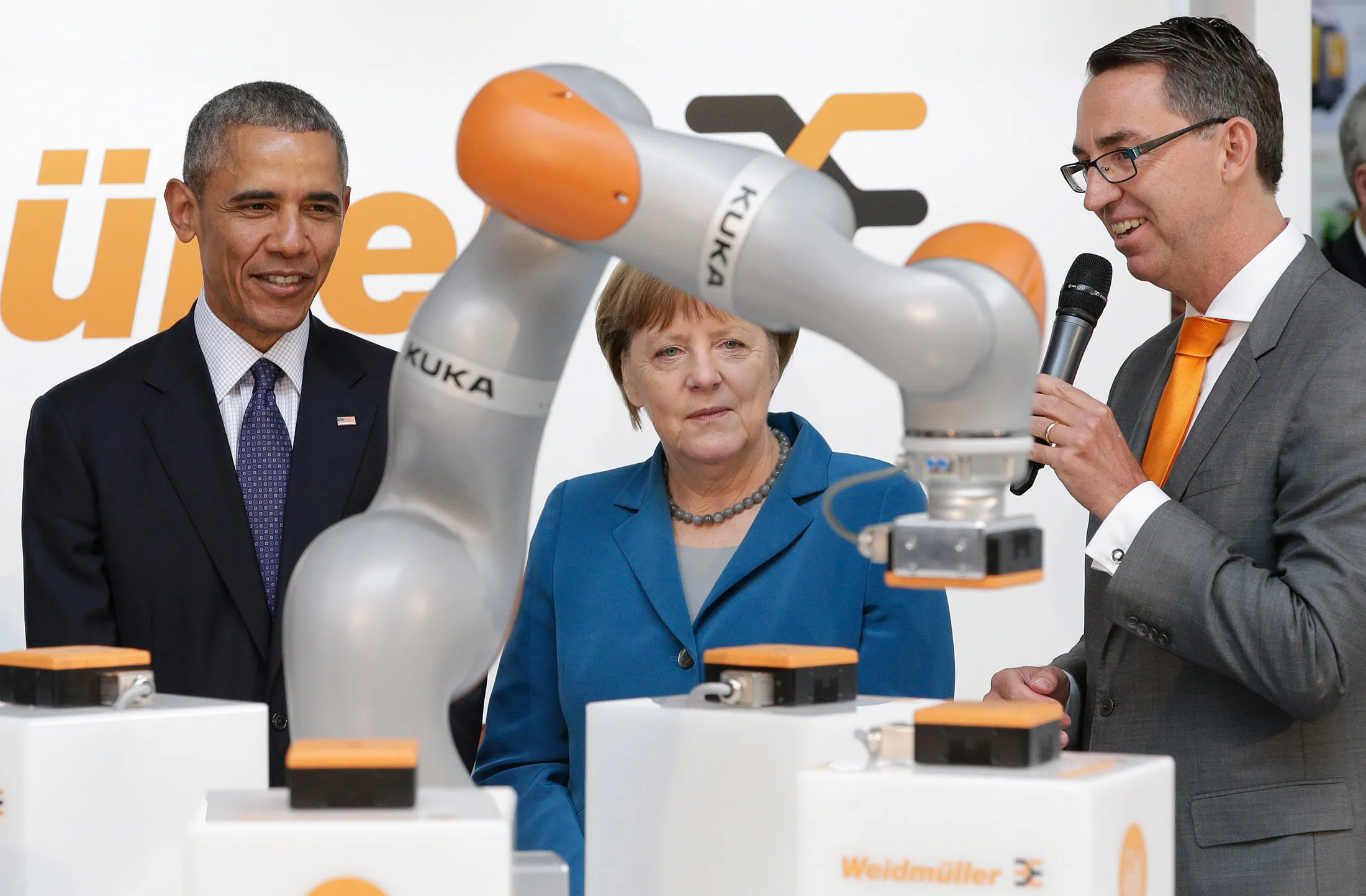 U.S. President Barack Obama, left, and German Chancellor Angela Merkel listen to robotic device maker Kuka CEO Till Reuter as they tour the Hannover Messe, the world's largest industrial technology trade fair, in Hannover, northern Germany, on April 25.
