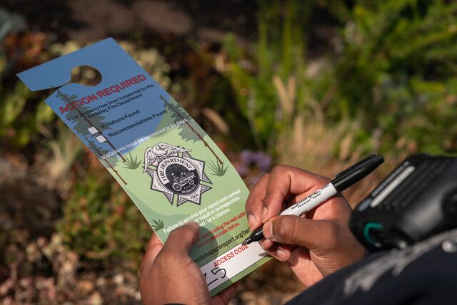 A fire inspector completes a door tag notifying homeowners of any violations and where to download an inspection report.