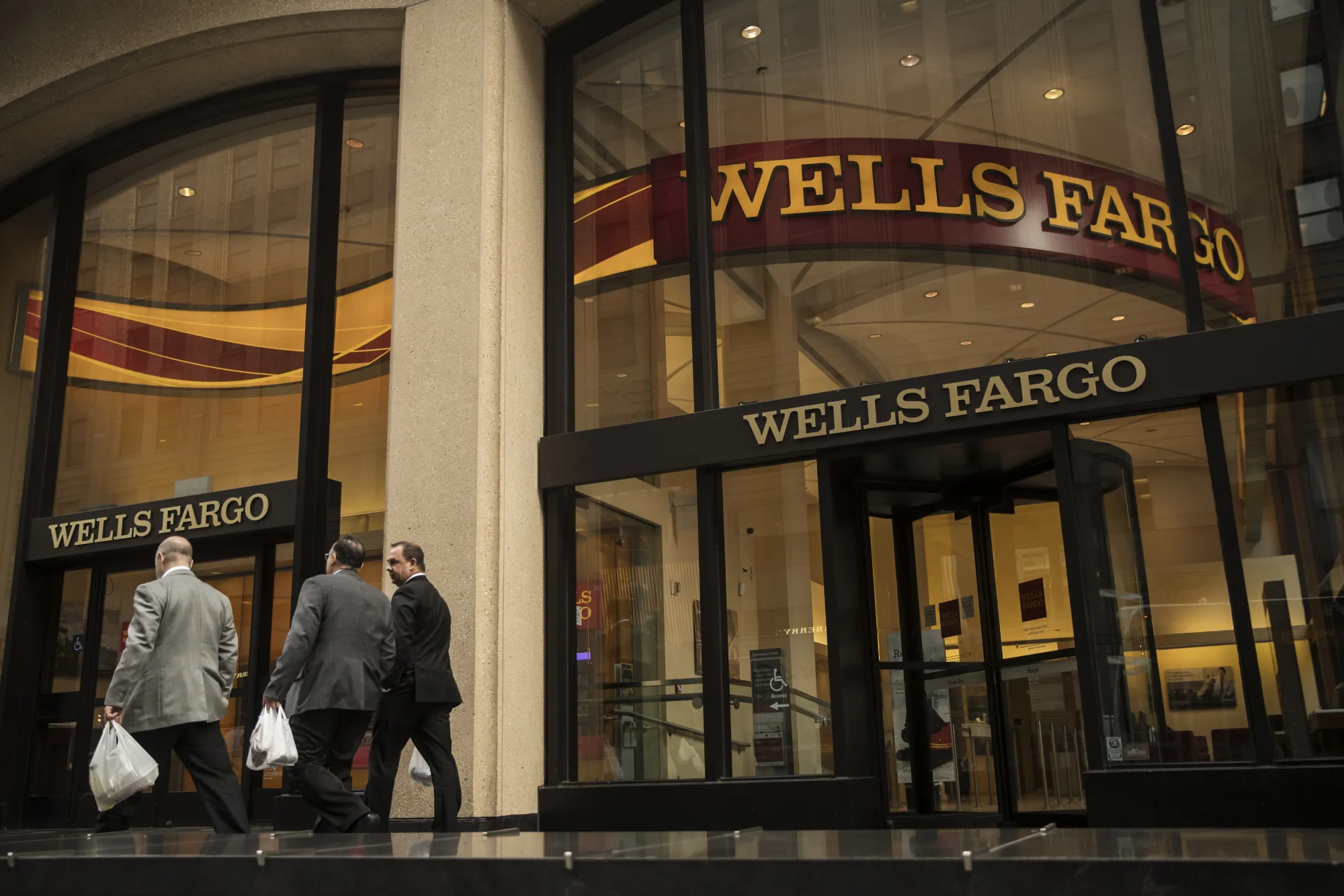 Pedestrians pass in front of a Wells Fargo &amp; Co. bank branch in New York.