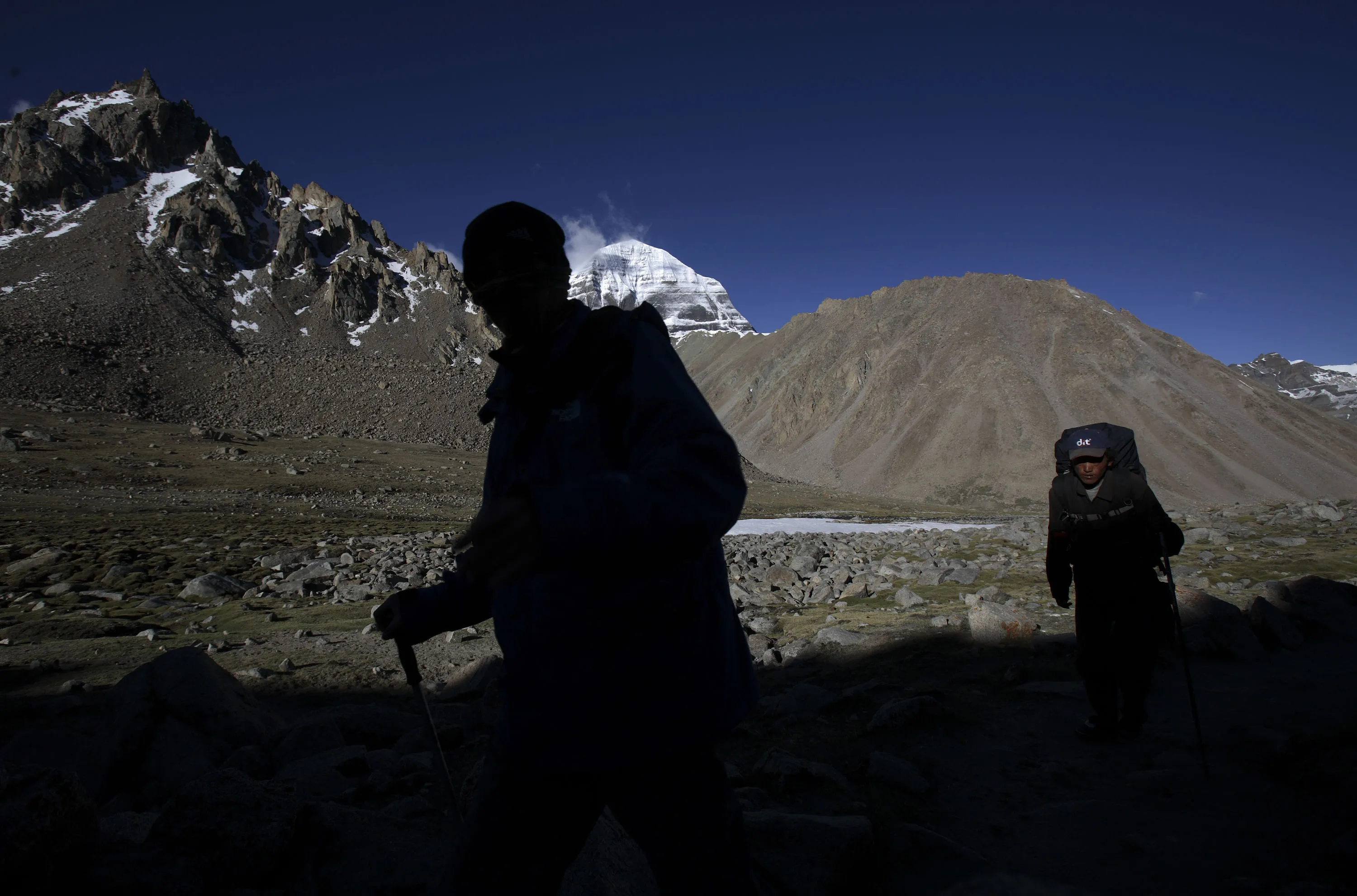 A pilgrim and the porter hike around Mt. Kailash in Purang County of Tibet Autonomous Region.