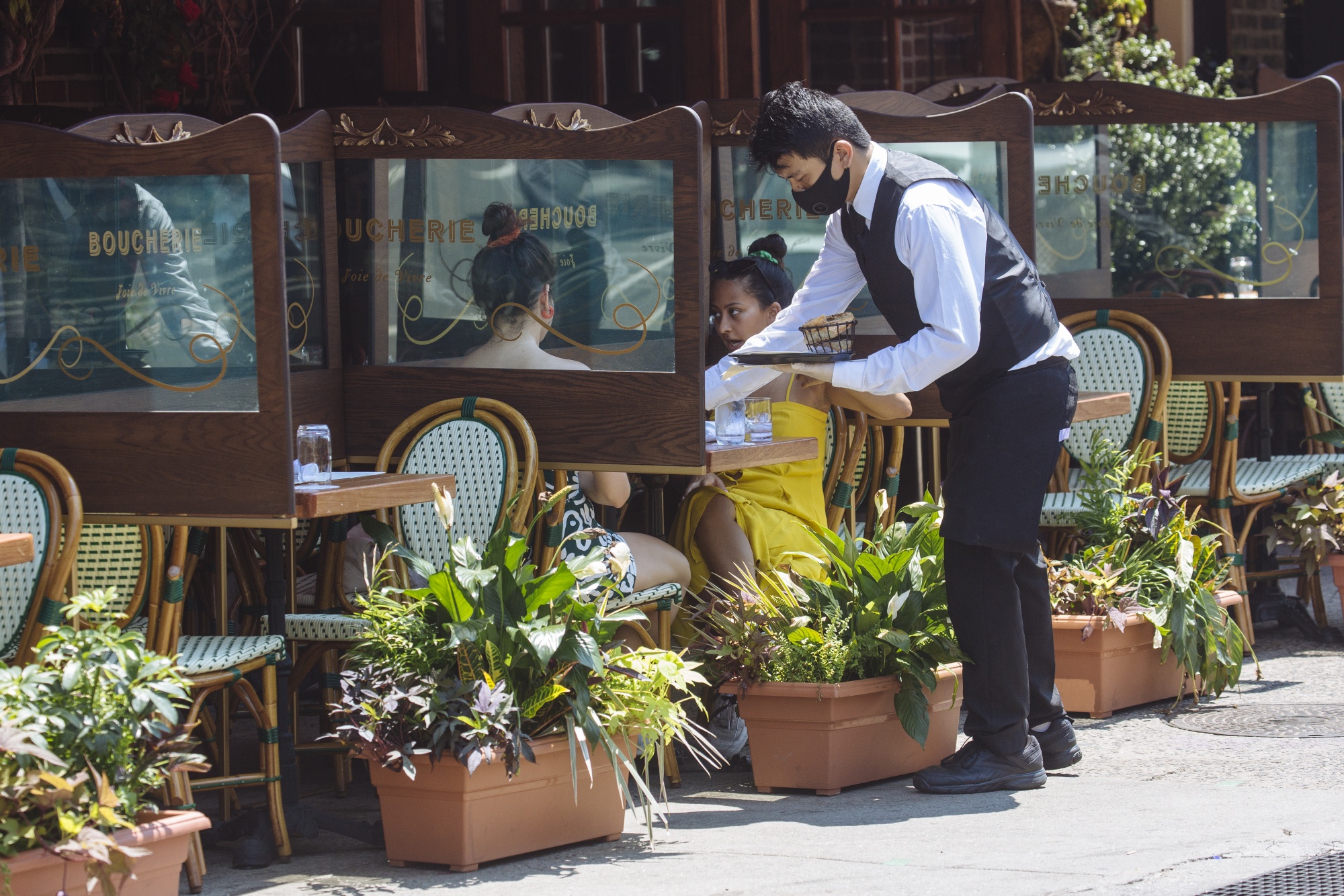 A server assists customers dining outside at a restaurant in the Greenwich Village neighborhood of New York on&nbsp;July 6.&nbsp;